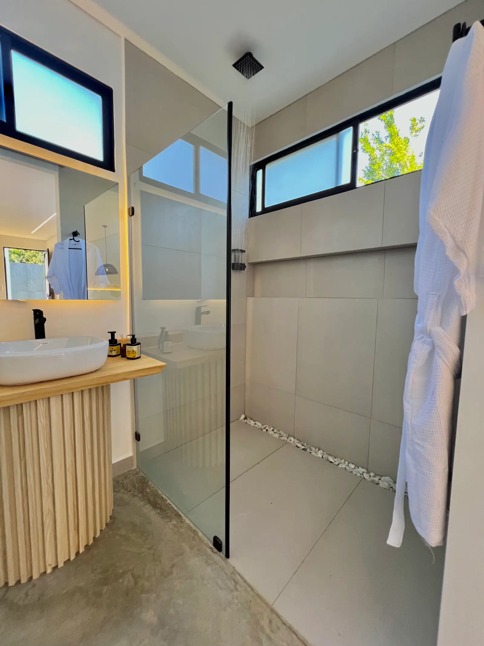 Baño de la cabaña Deluxe: ducha de vidrio, lavamanos de cerámica sobre madera y bata colgada