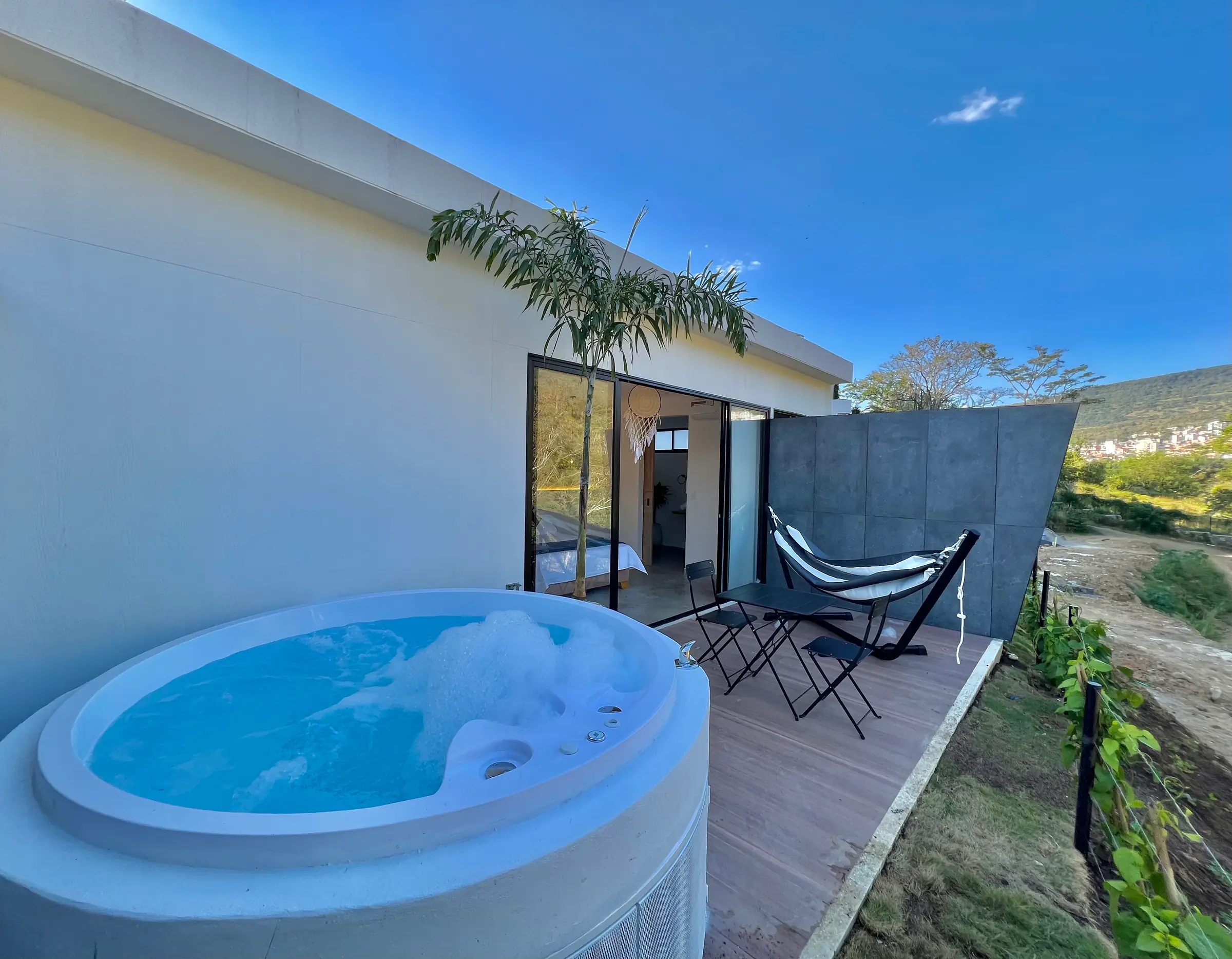 Jacuzzi privado con burbujas en la terraza de la cabaña Deluxe, con la hamaca y la montaña
