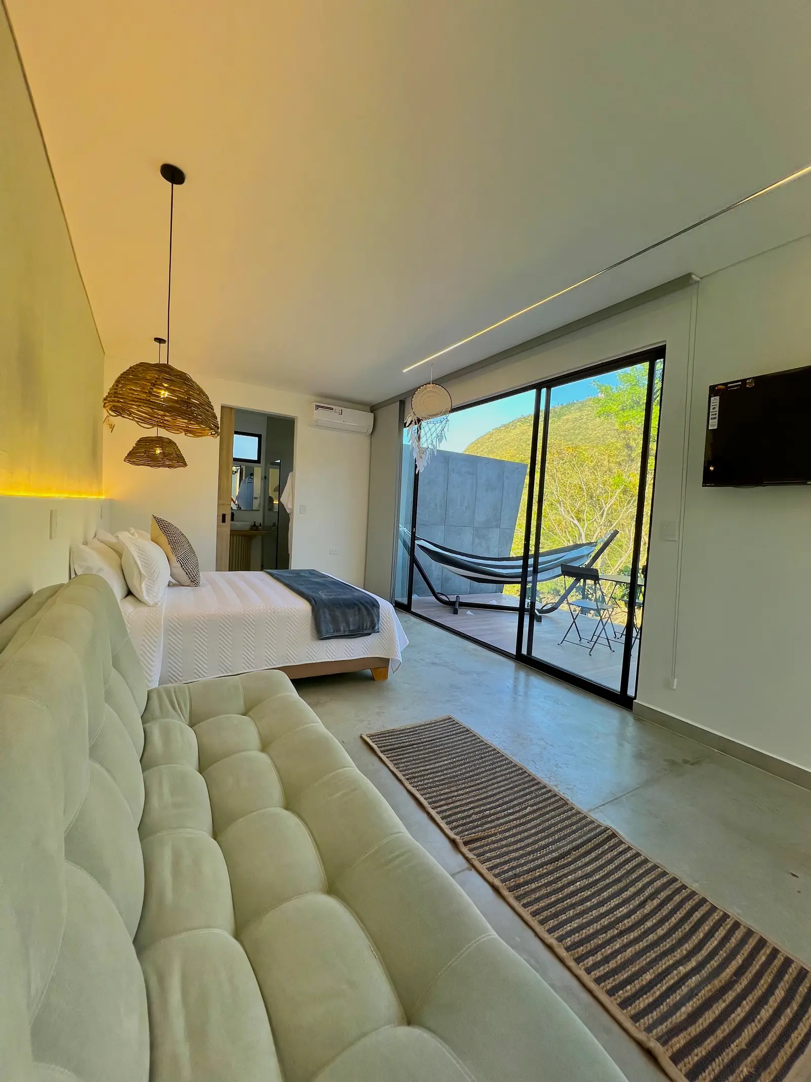 Sofá capitoneado a los pies de la cama de la cabaña Deluxe, con luz cálida