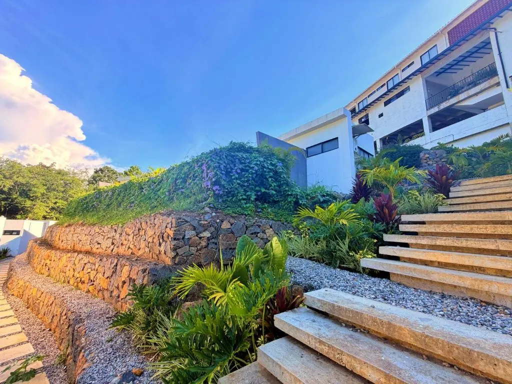 Escalones de piedra y madera entre jardines que bajan hacia las cabañas