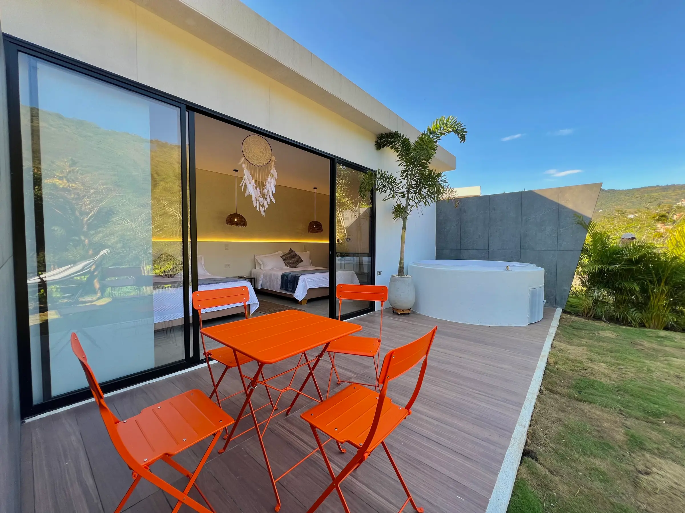 Terraza de la cabaña Familiar con mesa y sillas naranjas junto al jacuzzi