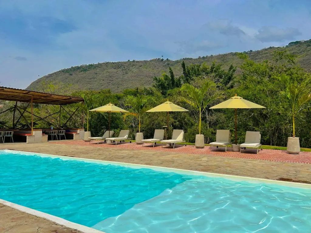 Piscina de la sede con tumbonas y sombrillas amarillas, y la montaña detrás