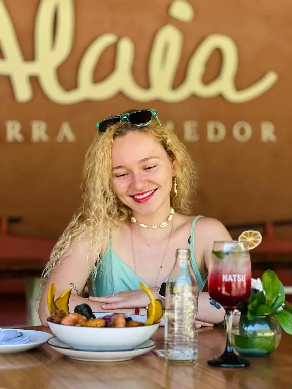 Huésped con un coctel y un plato en una mesa de Alaia